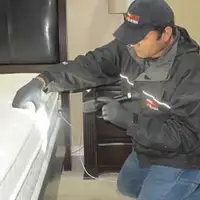 Bed bug inspection technician checking a mattress and bed frame for signs of infestation in Bellevue, WA